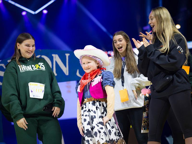 Penelope Ciancaglini walks the runway during a THON™ fashion show while students cheer her on.