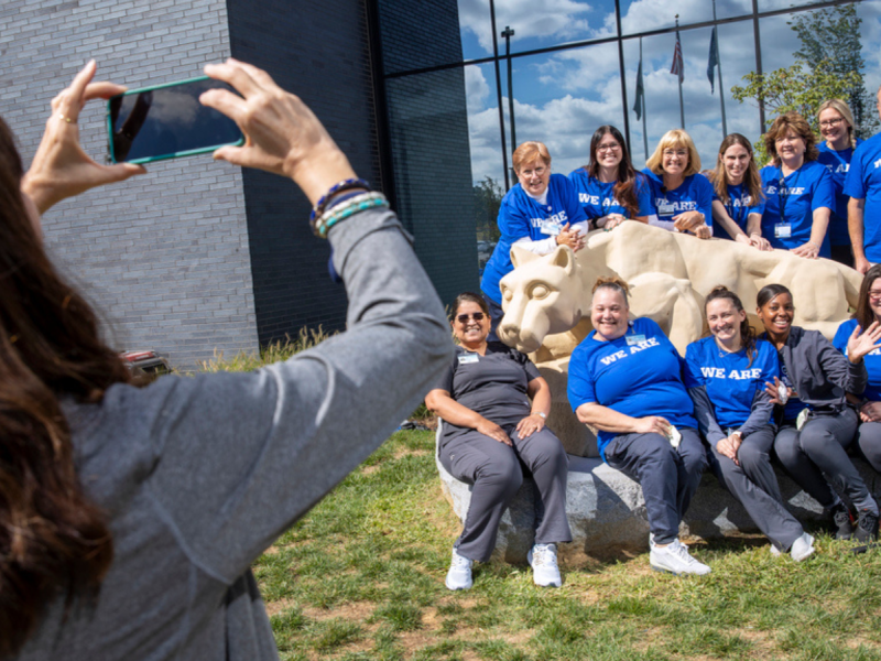A person is taking a photo of a group of people sitting on a hill.