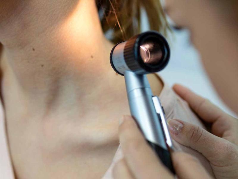 A dermatology doctor examines the skin of a patient's neck. 