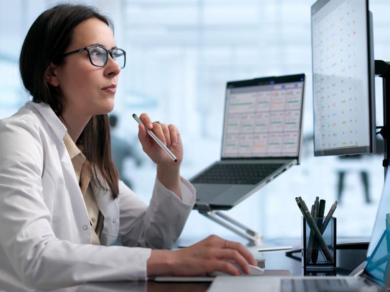 Healthcare manager reviews medical data on laptop for patient care.