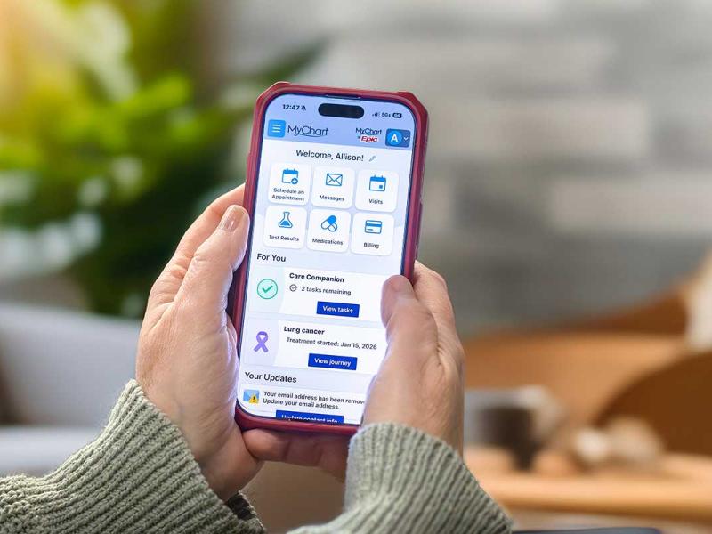 Close-up of hands holding a cell phone. On the screen is the MyChart Penn State Health app home screen. 