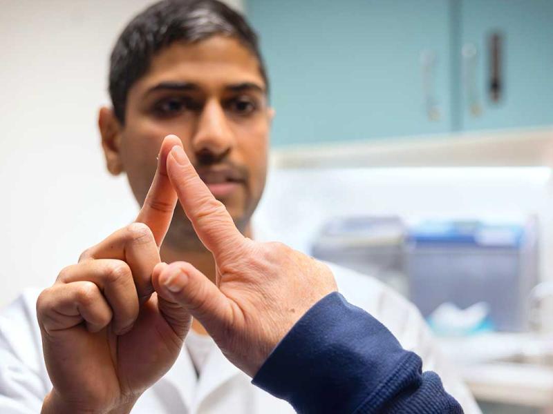 Dr. Varun Patel guides a patient through a finger‑tracking test in an exam room.