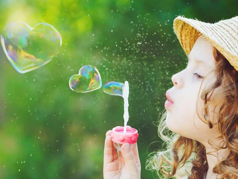 Young girl blowing heart bubbles