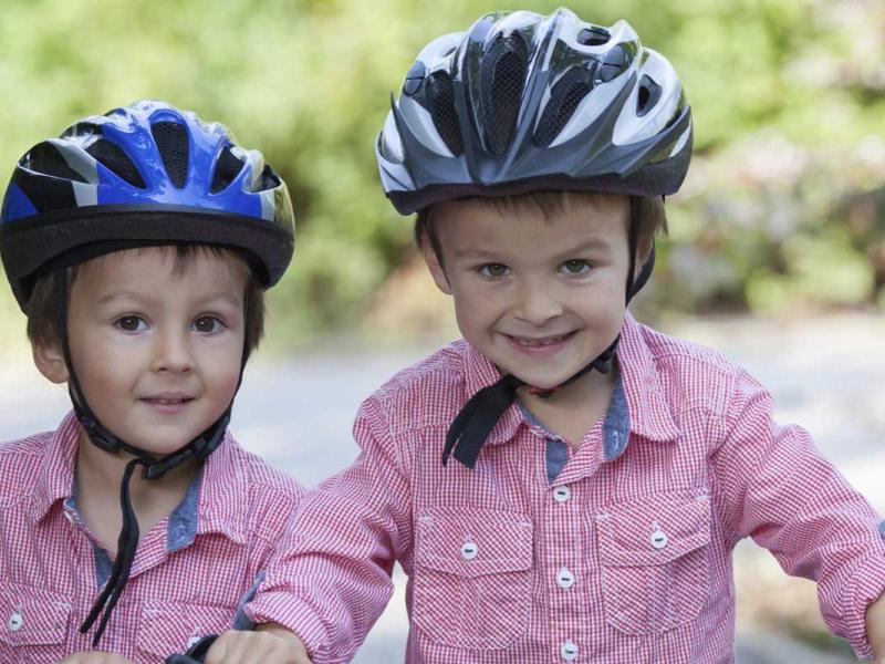 Two young boys wearing bike helments standing outside