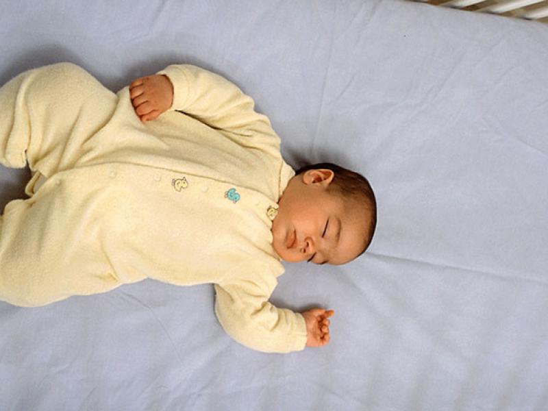 Keep your baby safe while sleeping. Baby sleeping in a white crib with blue crib color.