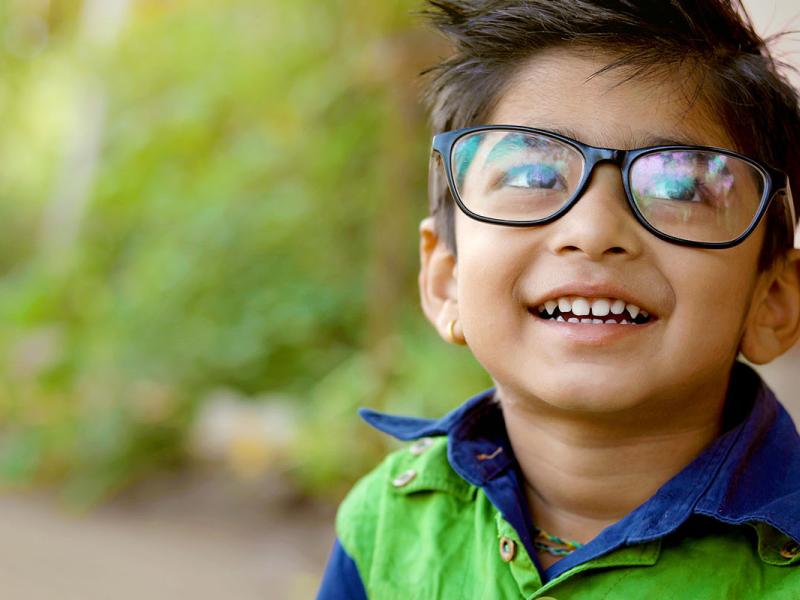 Happy boy wearing glasses with a bright green vest.