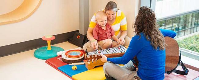 A caregiver does music therapy with a patient and his mother.